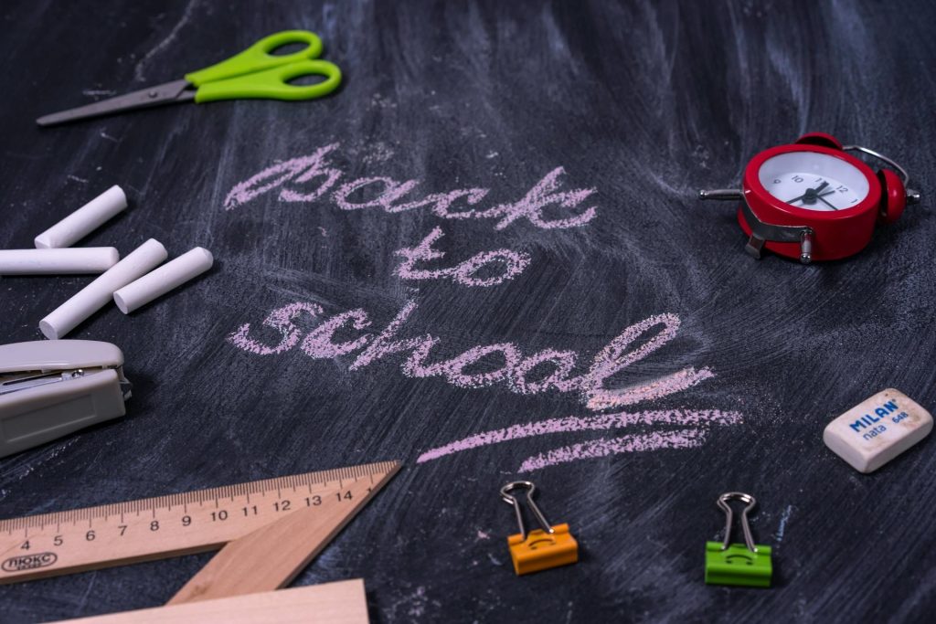 back to school written on a chalk board with school items around it