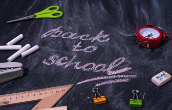 back to school written on a chalk board with school items around it